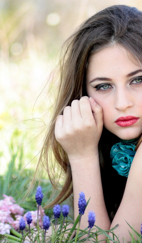 Молодая девушка брюнетка с голубыми глазами лежит на траве 