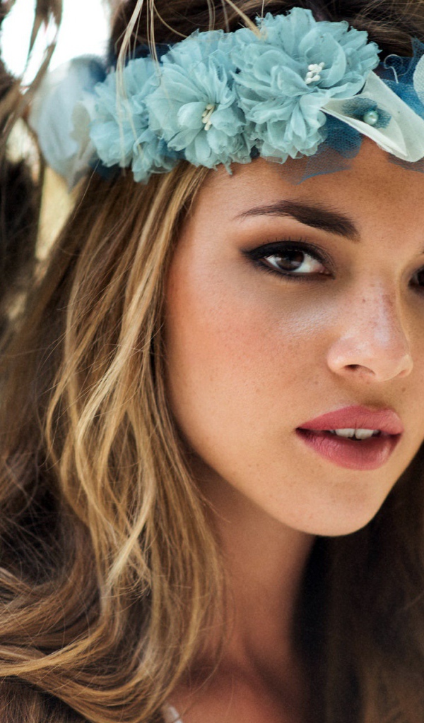 Молодая девушка модель с венком из голубых цветов на голове 