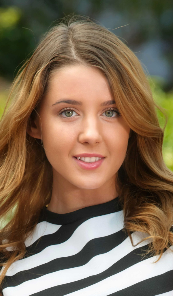 Молодая улыбающаяся девушка в полосатом платье