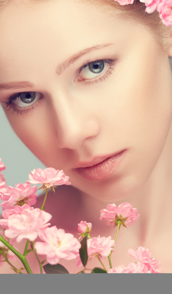 Молодая нежная девушка с розовыми розами на сером фоне