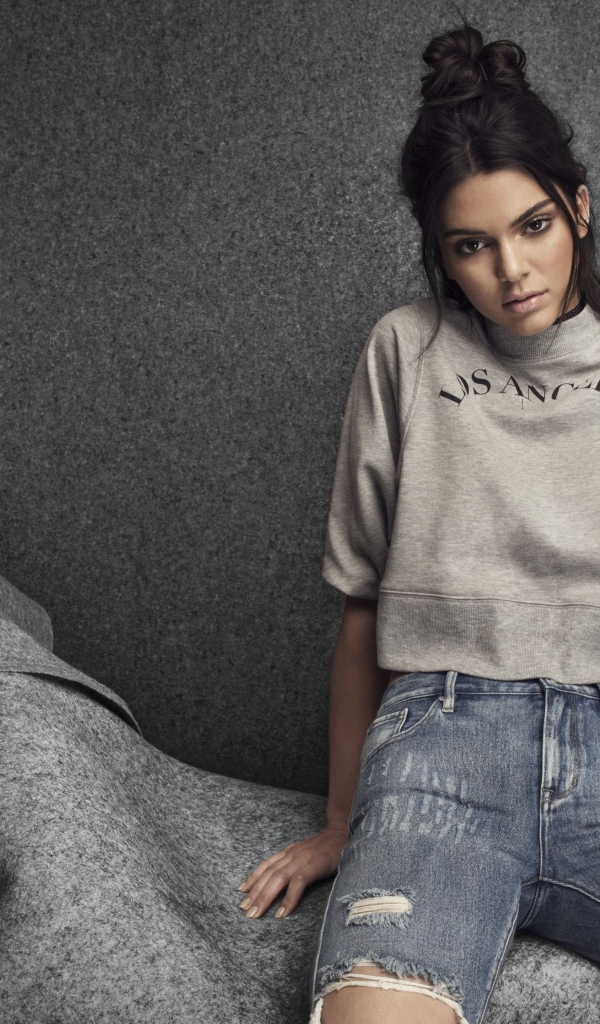 Модель Кендалл Дженнер в рваных джинсах на сером фоне