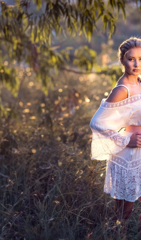 Молодая девушка модель в красивом белом платье с косой на голове