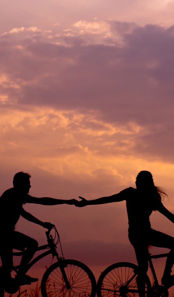 Влюбленная пара на велосипедах катается на закате