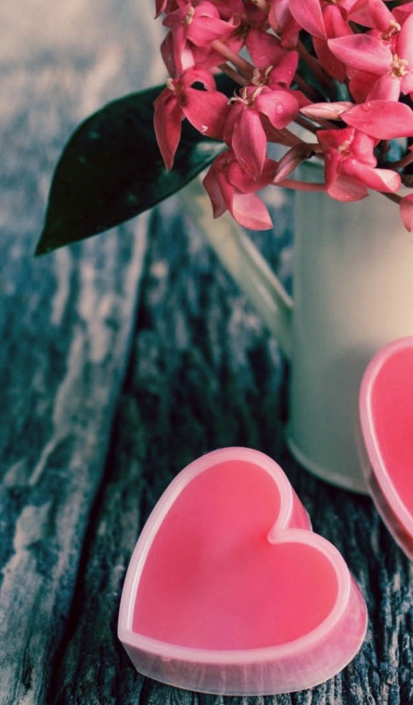 Розовые цветы в белой вазе и два розовых сердца 