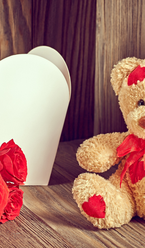 Плюшевый медведь с большим белым бумажным сердцем и красными розами