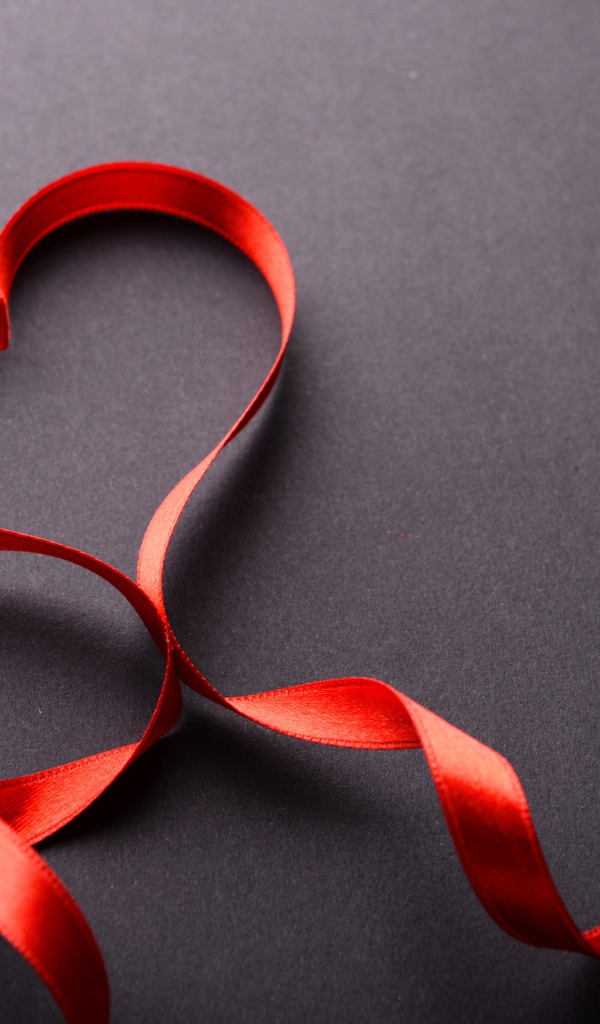 Красное сердце из атласной ленты на сером фоне