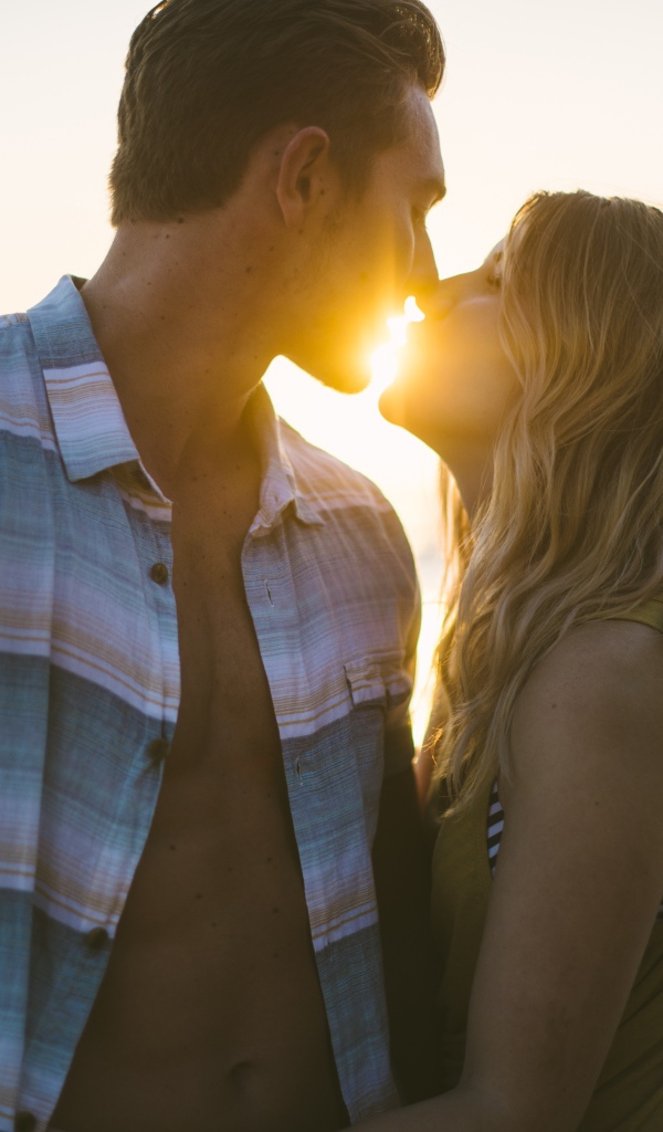 Романтический поцелуй влюбленной пары на закате солнца