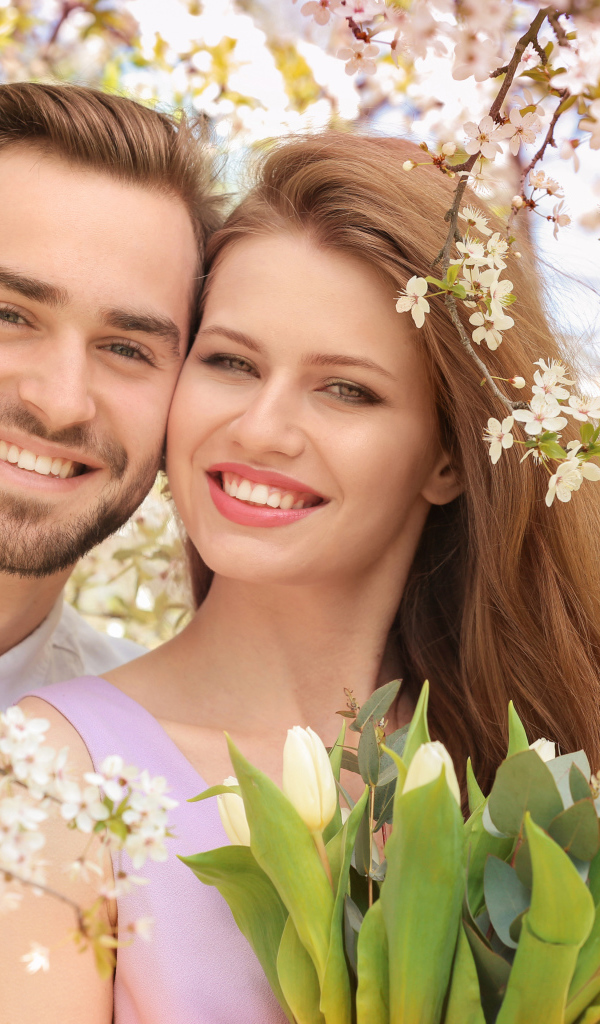 Улыбающаяся влюбленная пара у цветущего дерева