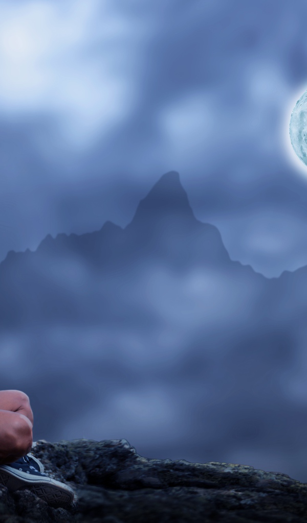 Мужчина медитирует на камне ночью в полнолуние