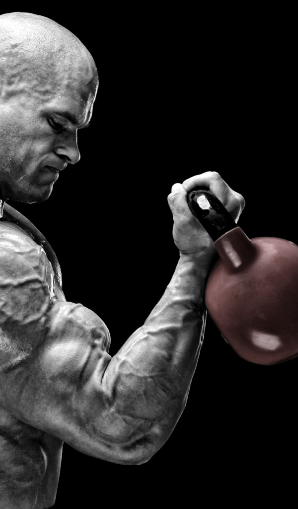 Сильный накаченный мужчина бодибилдер с гантелей в руках