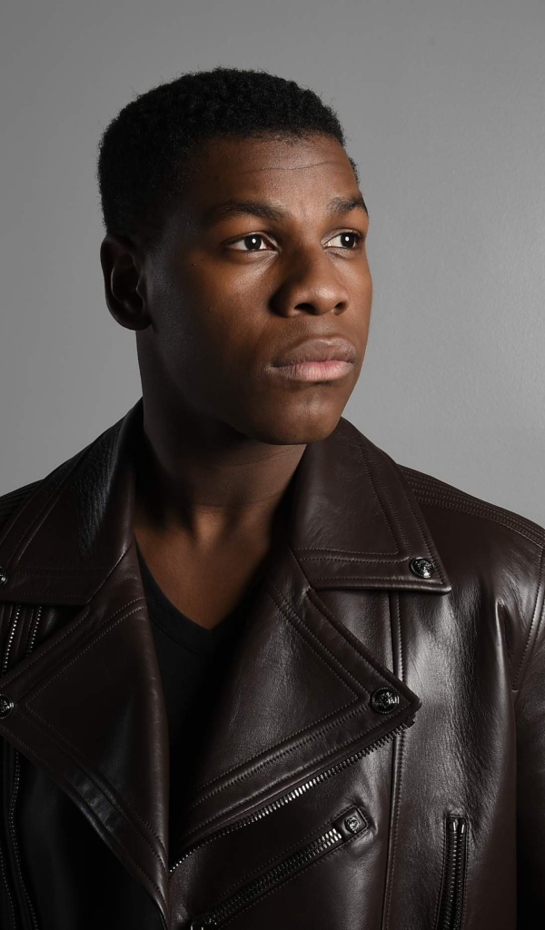 Актер  Джон Бойега в кожаной куртке на сером фоне