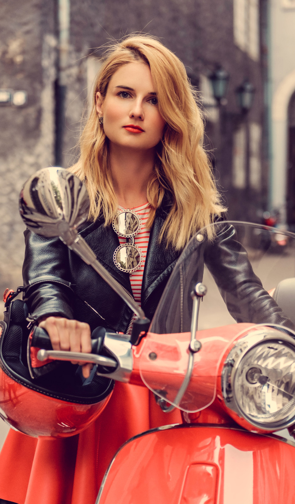 Beautiful blonde girl in a black jacket on a red motorcycle