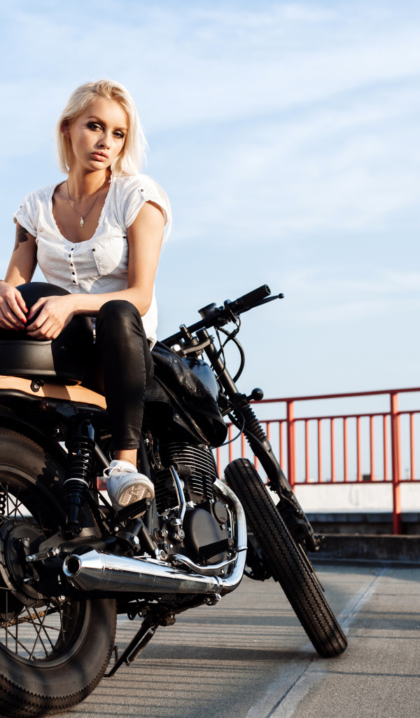 Beautiful blonde is sitting on a black motorcycle