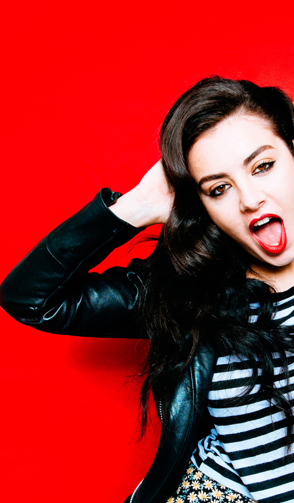 Американская певица Charli XCX позирует на красном фоне 