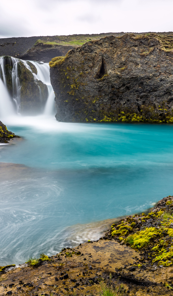 Красивый водопад между скалистых берегов 
