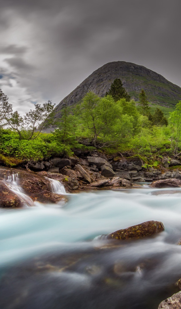 Быстрая вода в горной реке с маленьким водопадом 