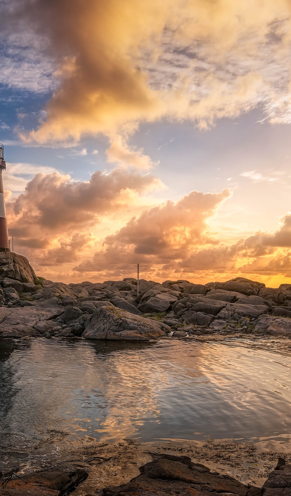 Маяк на каменном побережье на фоне красивого неба