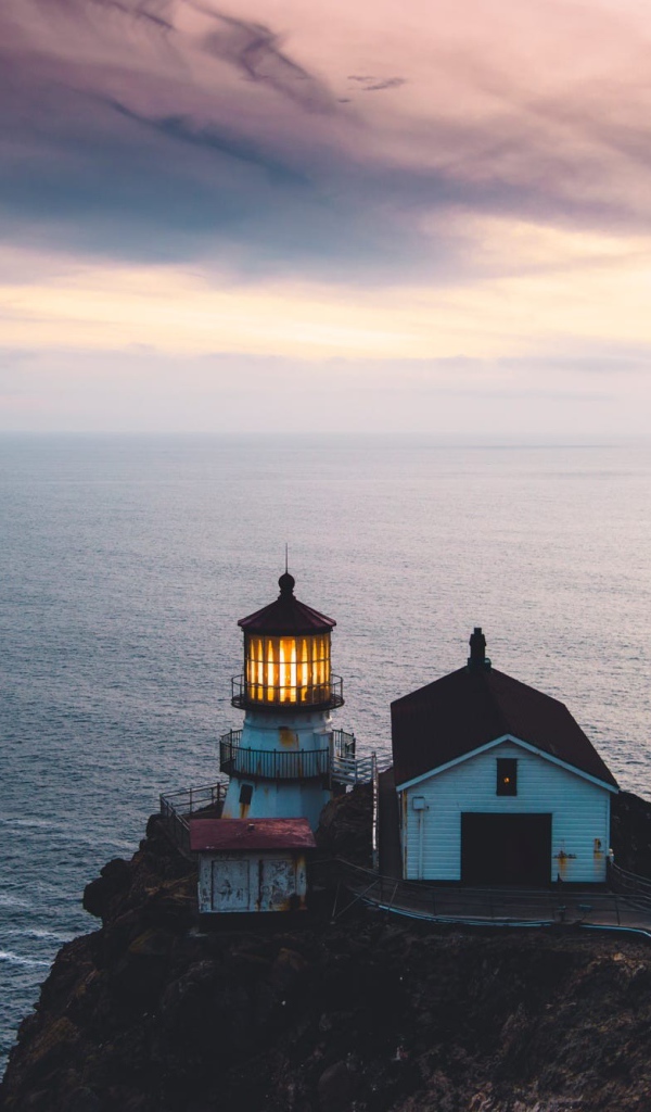 Маяк на скале на фоне горизонта океана 