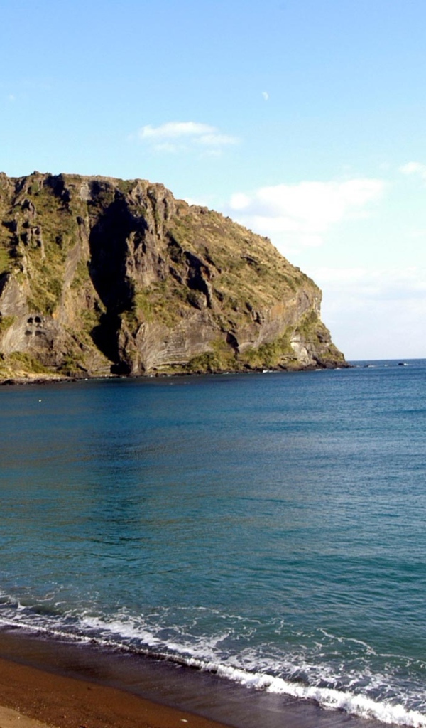 Гора на фоне спокойной воды моря под голубым небом