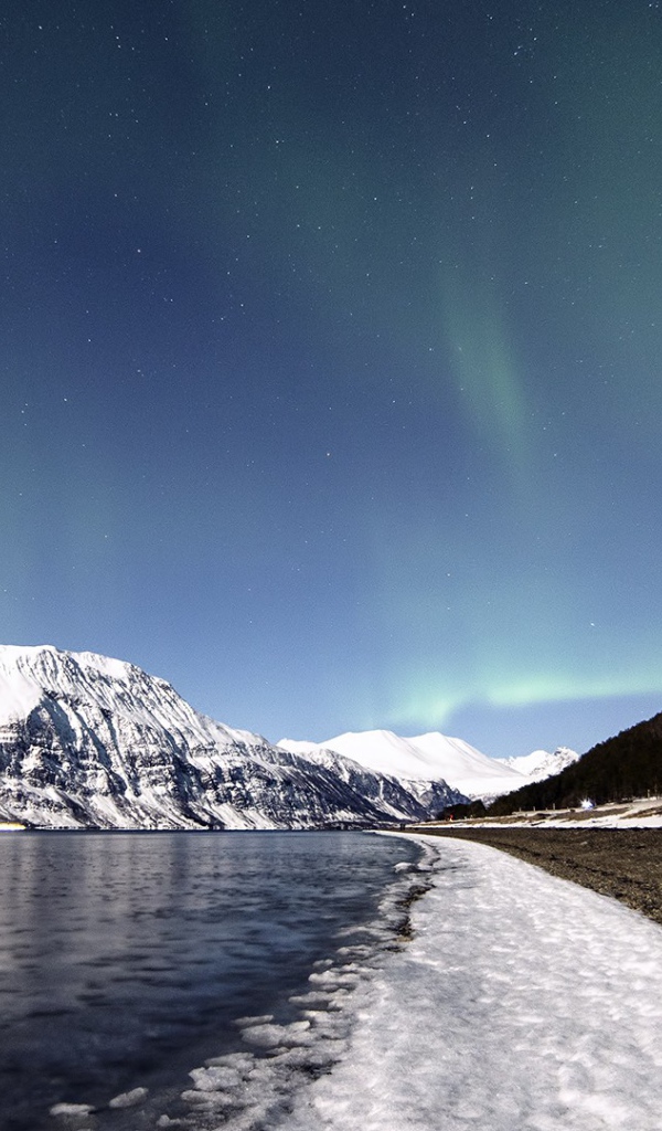 Северное сияние в небе над заснеженными горами 