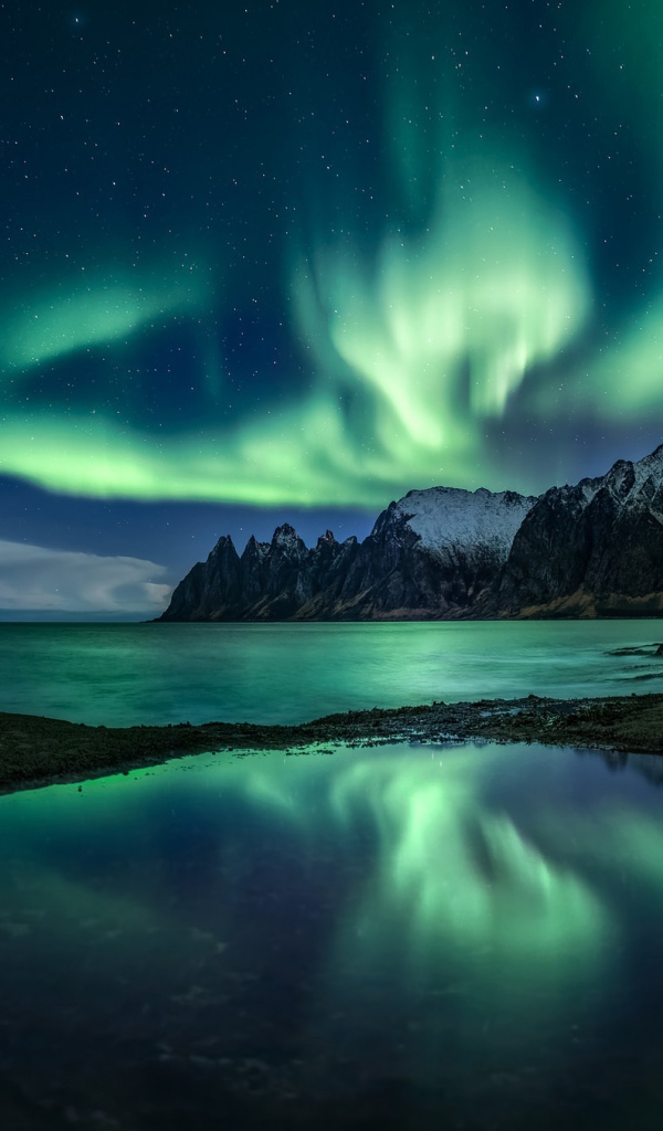 Северное сияние в звездном небе над горным озером 