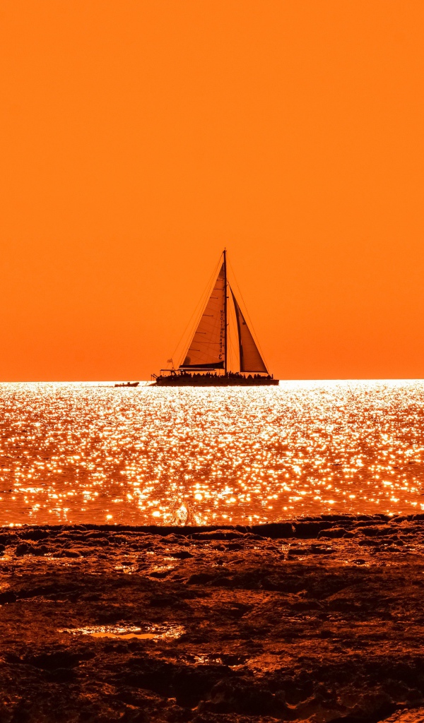 Парусная лодка на горизонте в океане на закате солнца