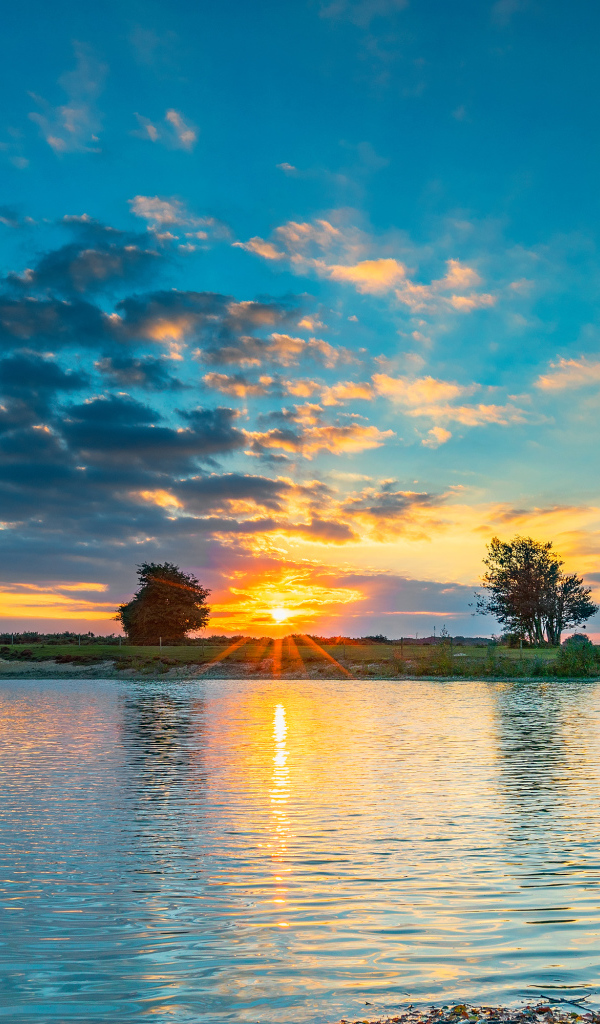 Закат солнца в небе отражается в воде озера 
