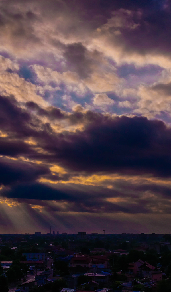 Лучи солнца пробиваются сквозь облака над городом