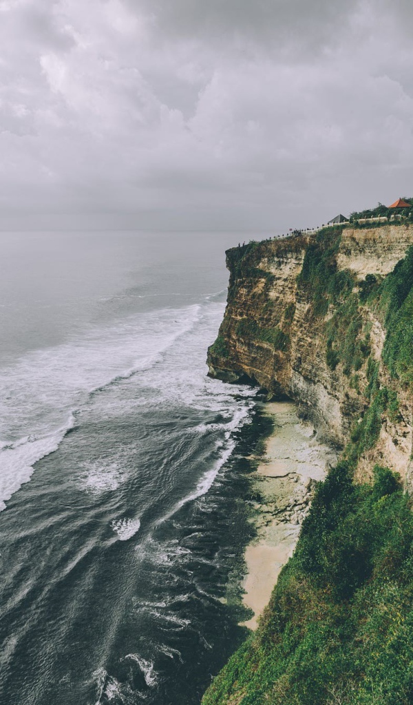 Бушующие волны у зеленого утеса 