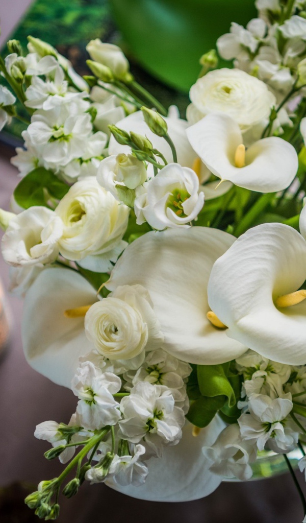 Букет белых цветов зантедеския и левкой с зажженными свечами на столе