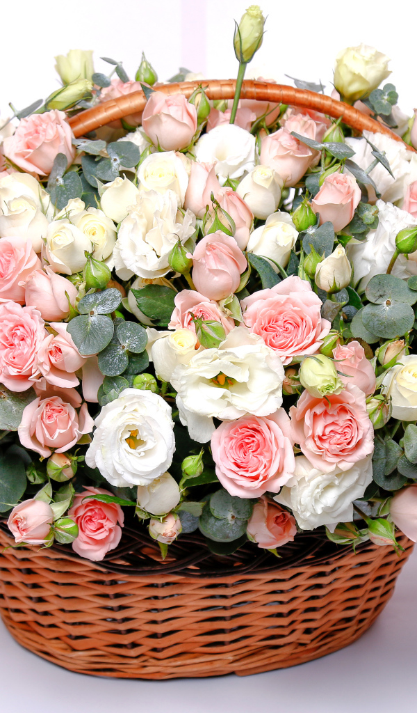 Корзина с красивым букетом цветов роз, эустомы на розовом фоне