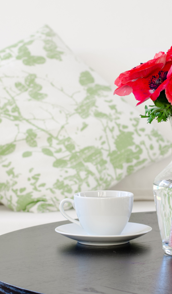 Букет красных цветов анемоны в вазе на столе с белой чашкой