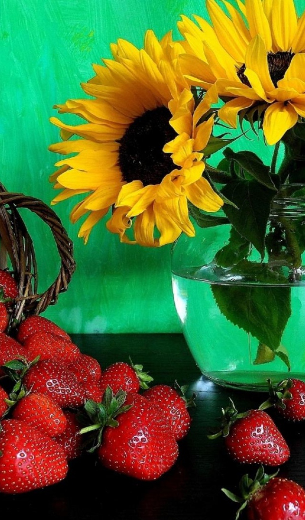 Цветы желтого подсолнуха в вазе со свежей клубникой 