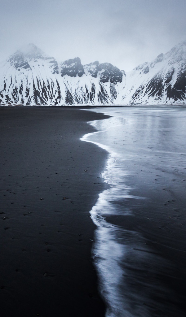 Заснеженные горы у пустынного пляжа