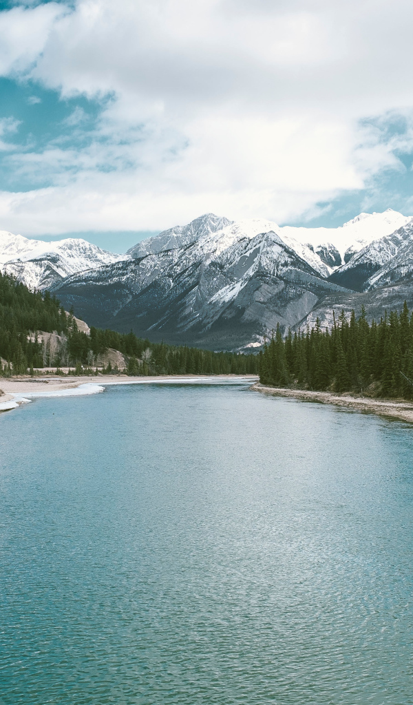 Чистая голубая вода в реке на фоне заснеженных гор 