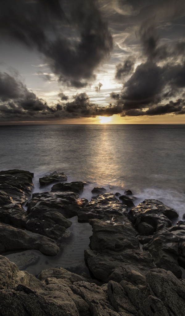 Низкие черные облака на закате в небе над океаном