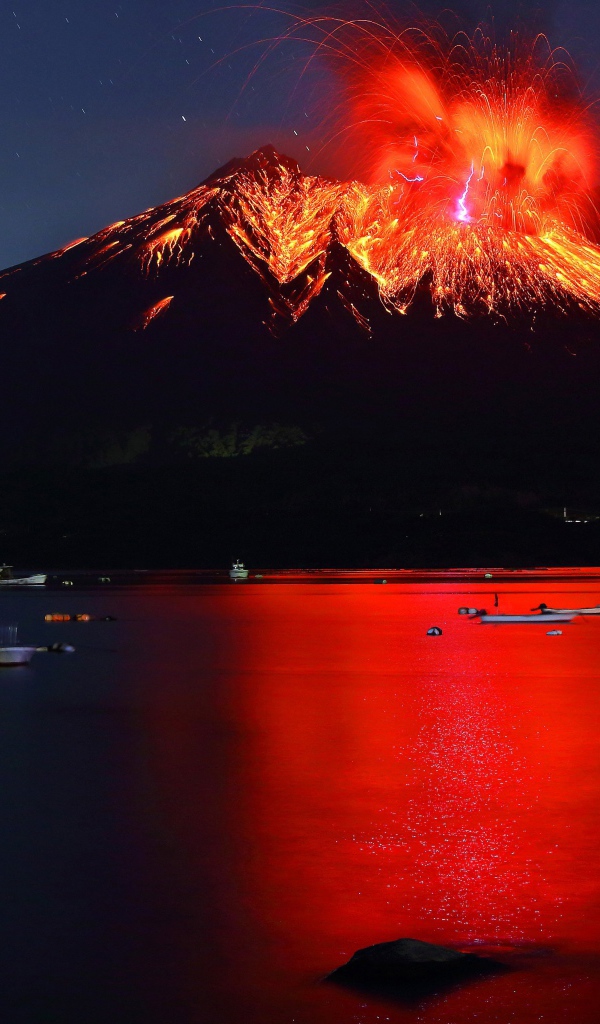 Вулкан Сакурадзима извергается  на фоне воды 