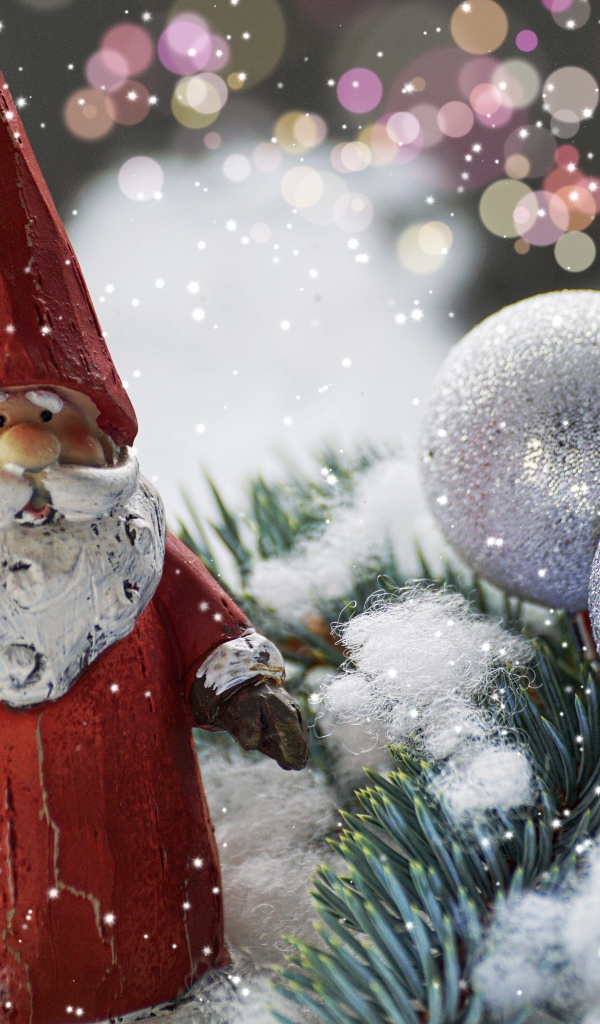 Статуэтка деда Мороза рядом с еловой веткой и яркими шарами