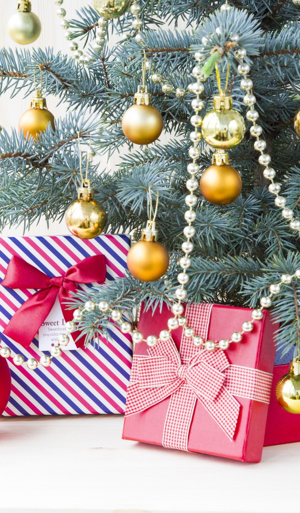 Подарки под зеленой наряженной елкой с золотыми шарами