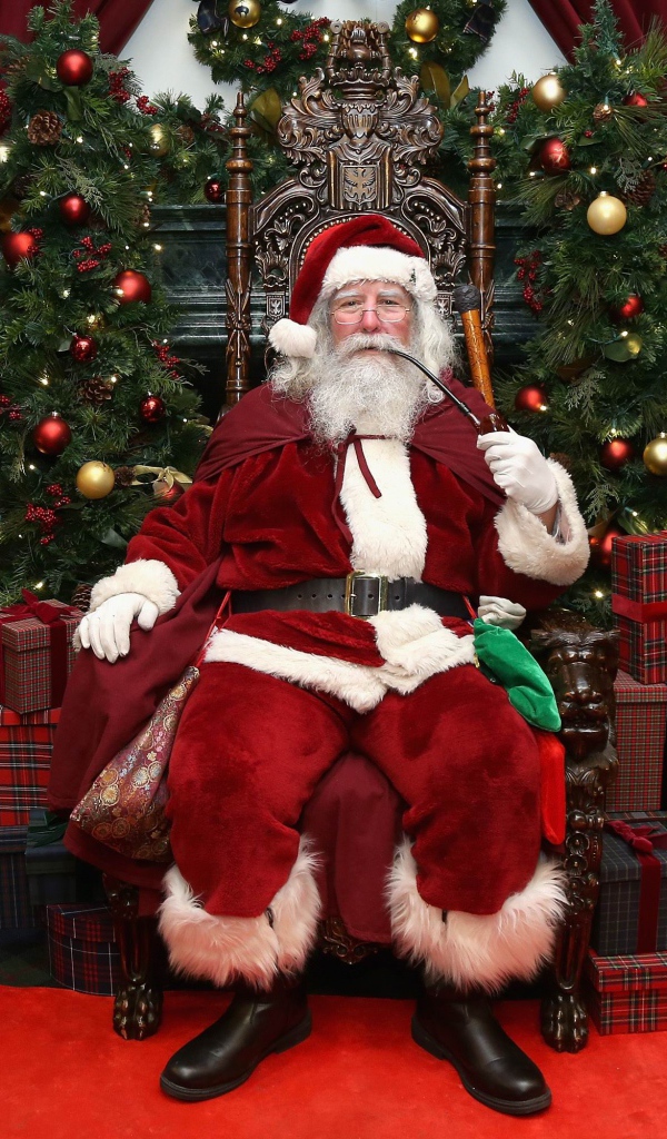 Санта Клаус курит трубку сидя в кресле