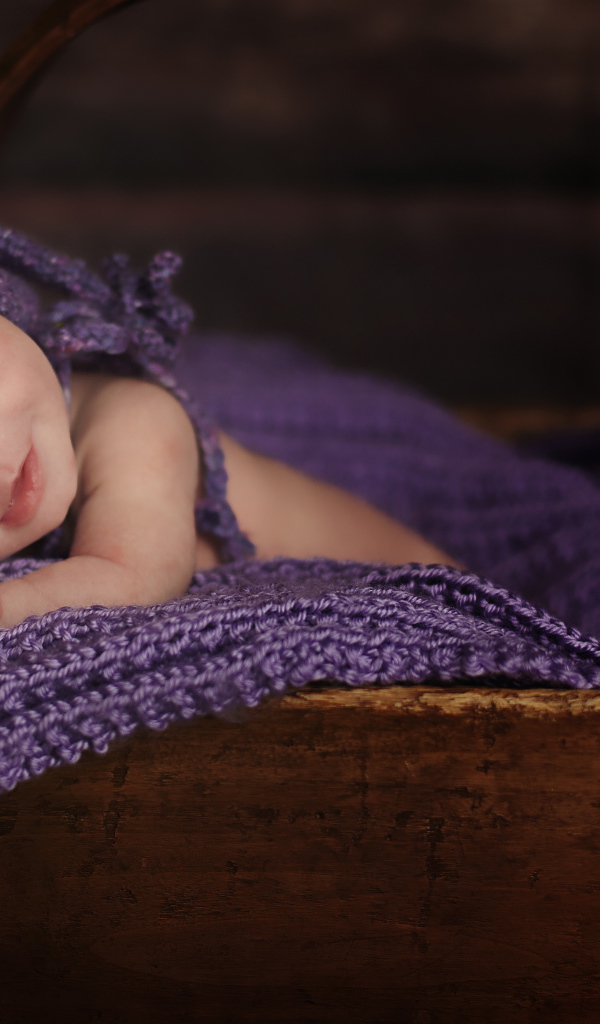 Грудной ребенок спит в деревянной корзине