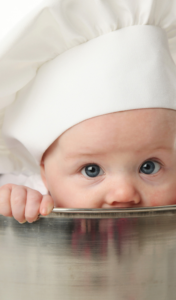 Грудной ребенок в шапке повара сидит в большой кастрюле