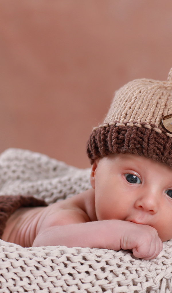 Грудной ребенок в вязаной коричневой шапке