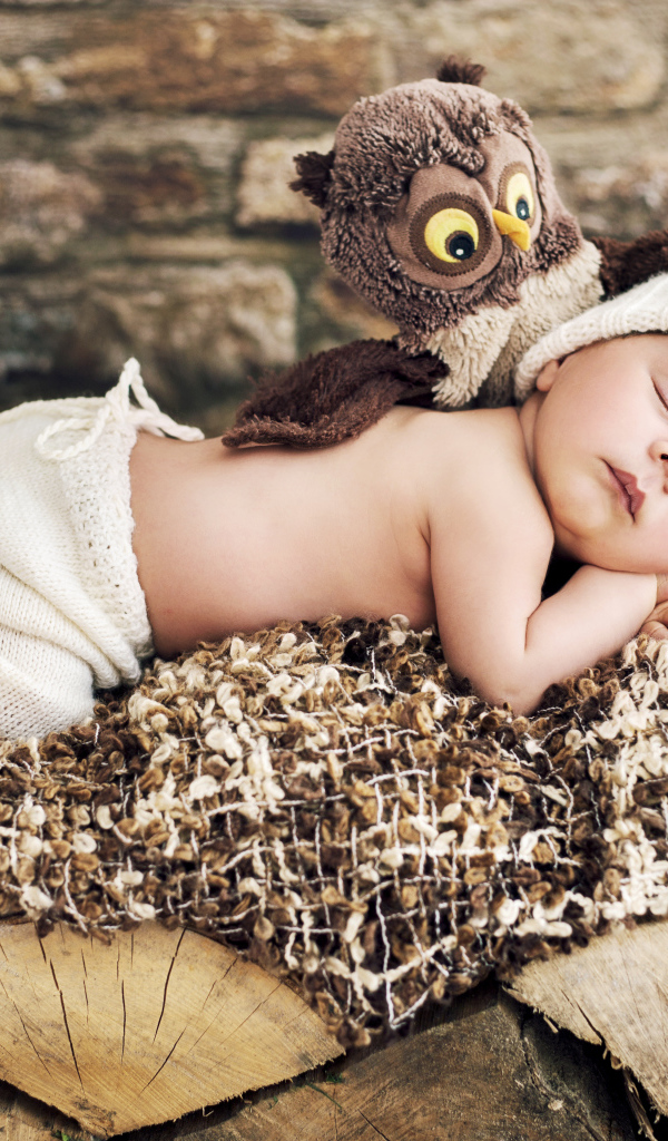 Грудной ребенок спит рядом с игрушкой совой