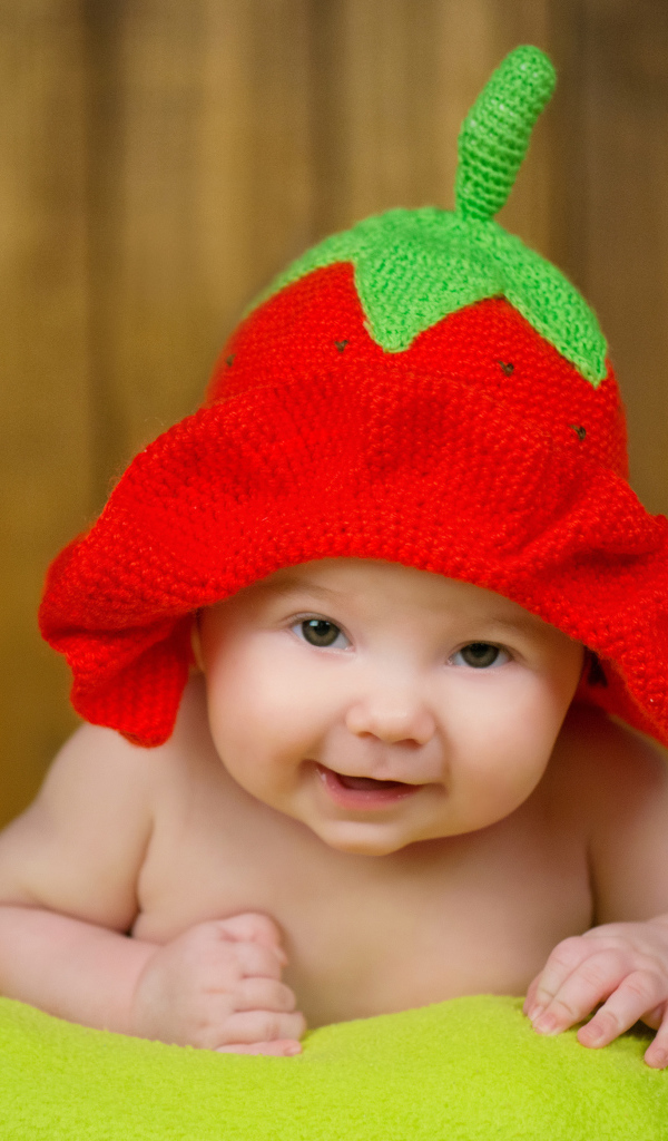 Младенец в забавной шапке клубнике на голове
