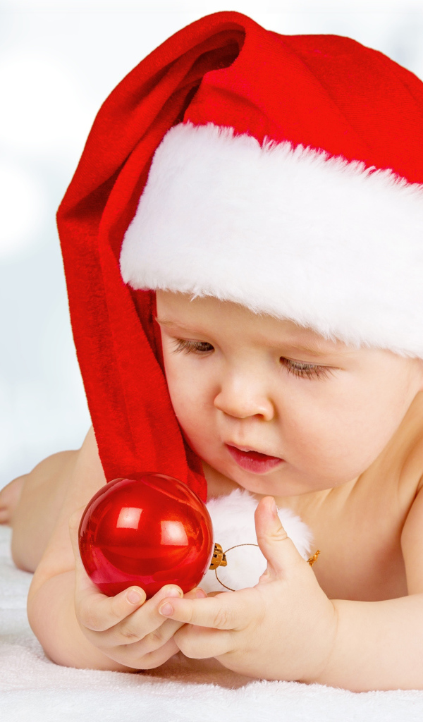 Младенец в красной новогодней шапке с елочными шарами на новый год