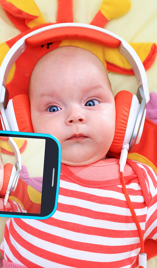 Младенец в оранжевых наушниках делает селфи