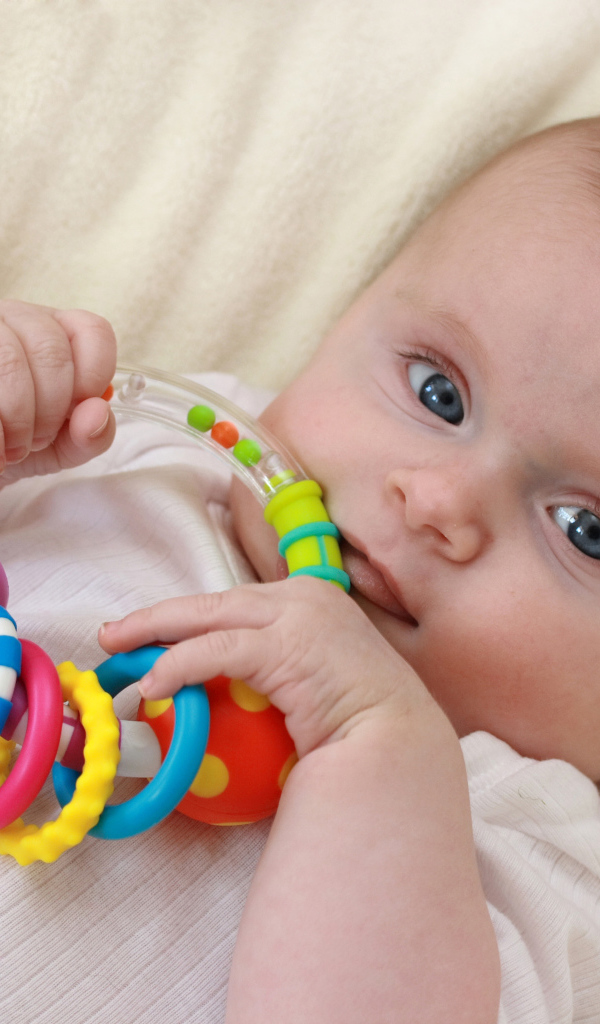 Грудной ребенок с погремушкой в руках