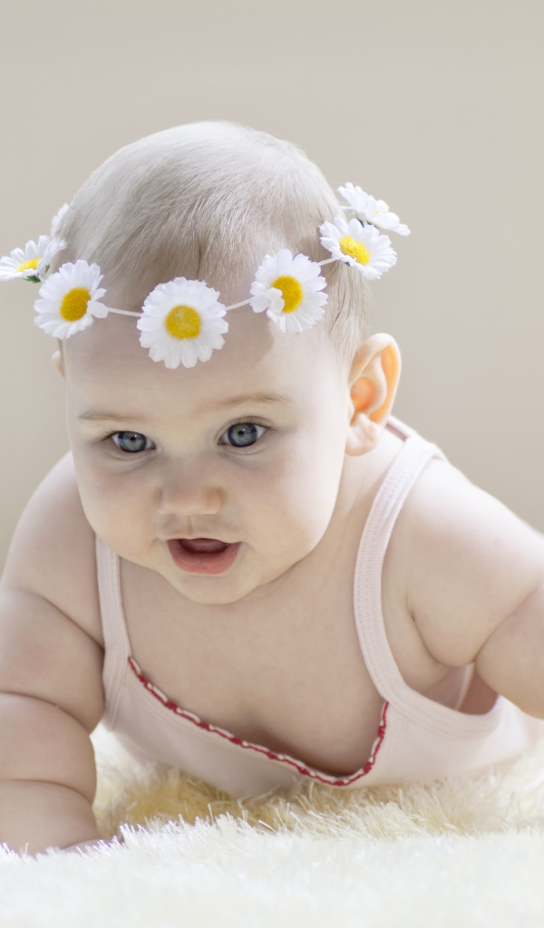 Грудной ребенок с венком из белых ромашек на голове