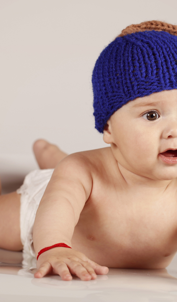 Грудной кареглазый ребенок в вязаной шерстяной шапке